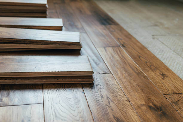 Individual panels of hardwood flooring sit on top of an installed floor.